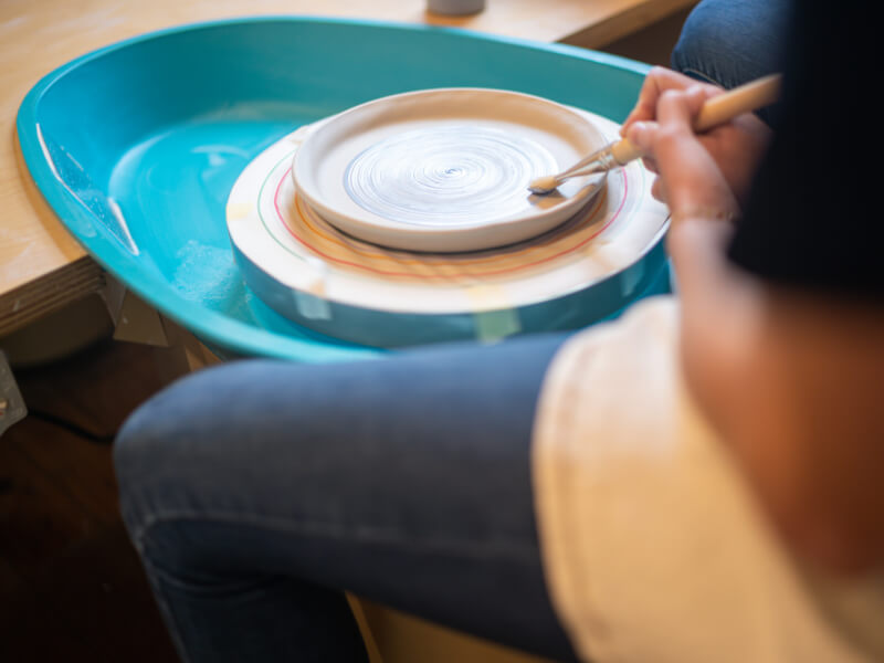 Overhead view of someone painting a round ceramic plate